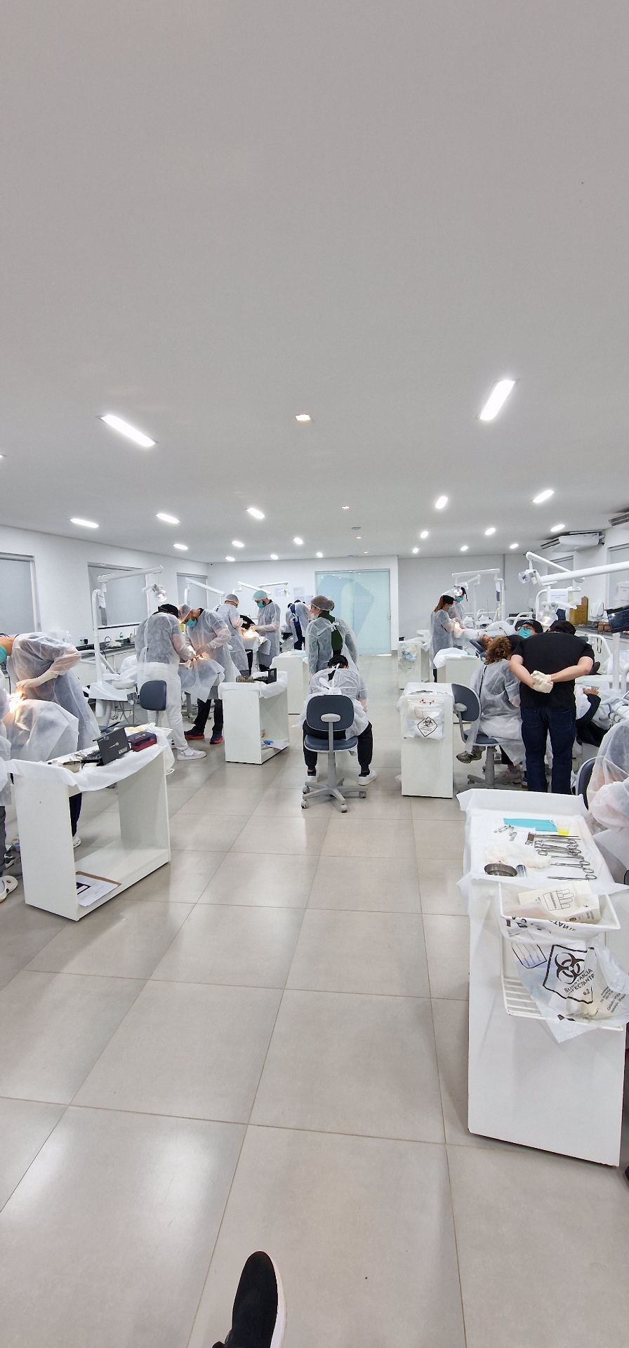 Sala clínica com vários alunos em prática durante uma edição anterior da formação